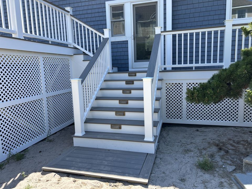 After: new stairs with white rails and lit risers to the back door, framed by lattice skirting