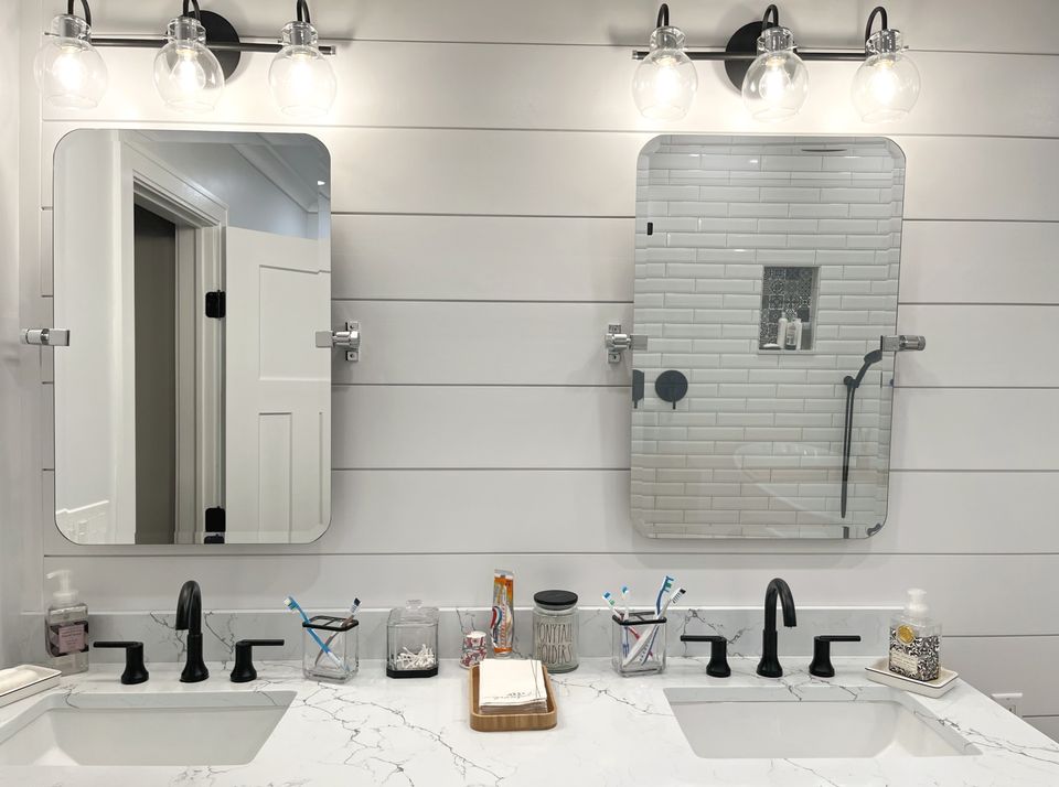 Double vanity with a shiplap wall, pivot mirrors, and black fixtures