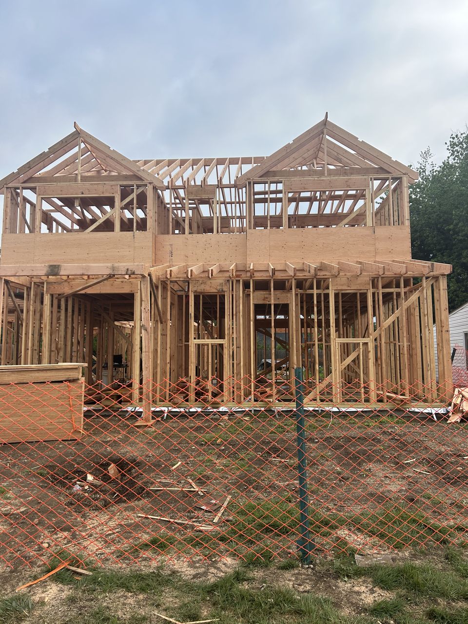 Front of a new build in framing behind a construction fence